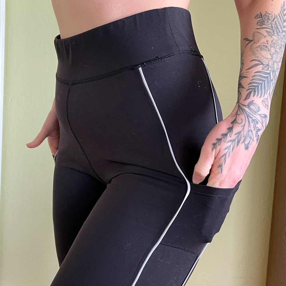 Black leggings with white pinstripes and mesh paneling on calf. Side pockets